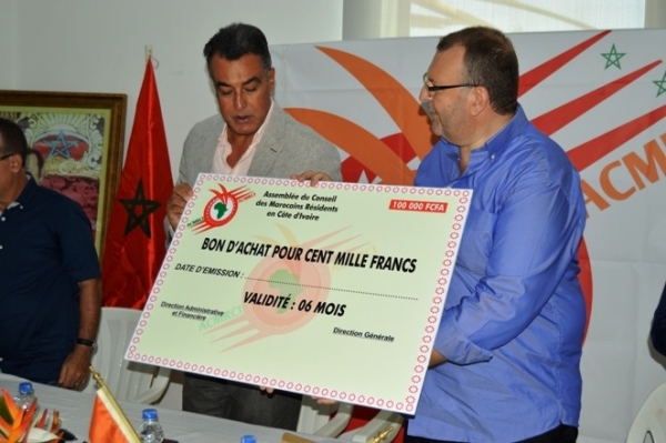 Le pr&eacute;sident de ACMRCI Ouazzani Chahdi (chemise bleu &agrave; droite) et l'ambassadeur du Maroc en C&ocirc;te d'Ivoire Abdelmalek Kettani (Veste &agrave; gauche) tenant un bon symbolique de 100.000 FCFA remis &agrave; une famille musulmane